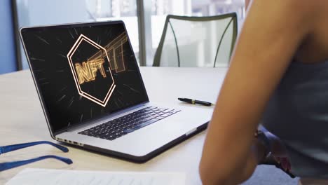 video de una mujer biracial trabajando en una computadora portátil con nft en la pantalla