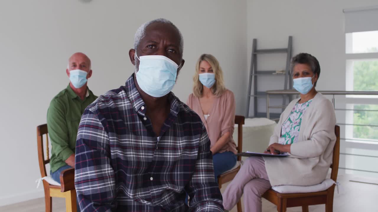 dos parejas mayores diversas sentadas en círculo teniendo una conversación de terapia en casa mirando a la cámara