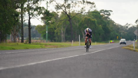 road cyclist followed by car on rural highway, 4k slow motion