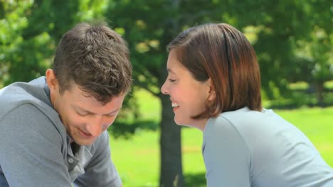 una pareja joven y amorosa hablando afuera.