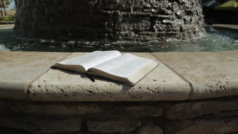 holy book by a peaceful water fountain background : dolly right