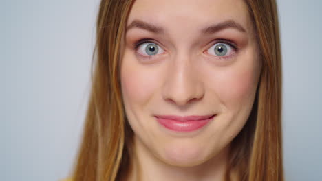 Closeup-surprised-woman-smiling-at-camera-on-grey-background.-Funny-girl-face