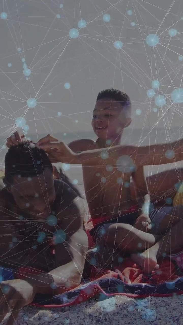Vertical video: Boy sitting on man on beach reaching tapping hair bonding health with blue nodes