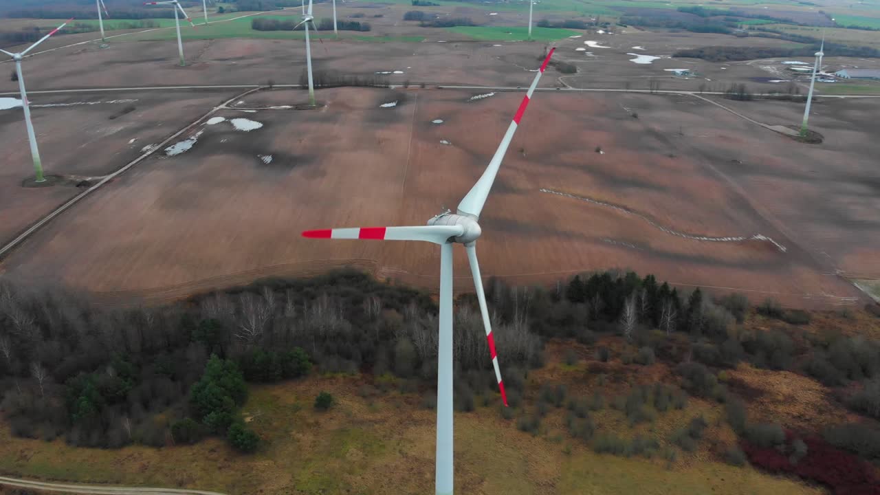 Camera goes circle around a windmill turbine producing sustainable green energy in the landscape background