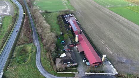 long farmers house with red tile and solar panel in american countryside. car driving on rural intersection road. frosty and cold winter day in usa. aerial top down flyover. silo storage in garden.