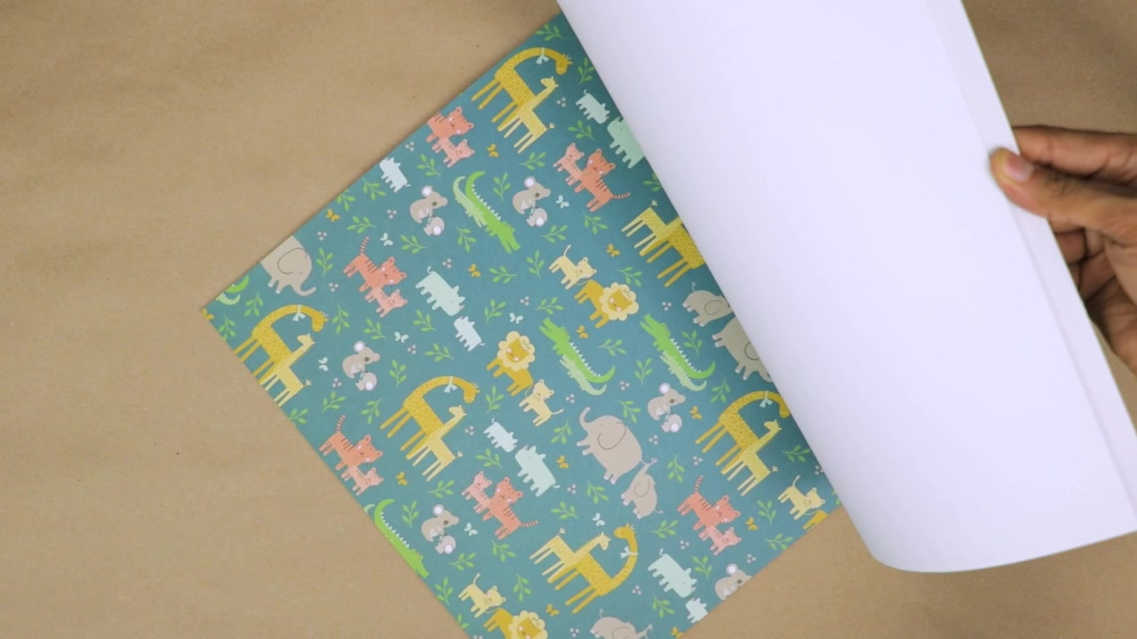Mano che gira una pagina di carta da scrapbooking a righe con un motivo a tema neonato