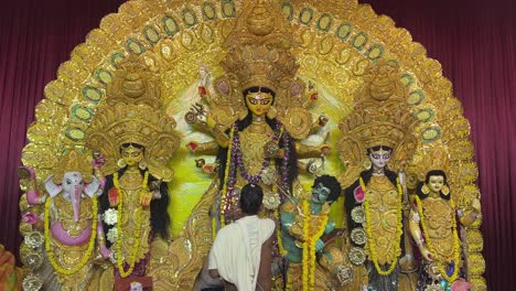 a priest is offering sandhi puja to goddess maa durga in a traditional look in a pandal in kolkata.