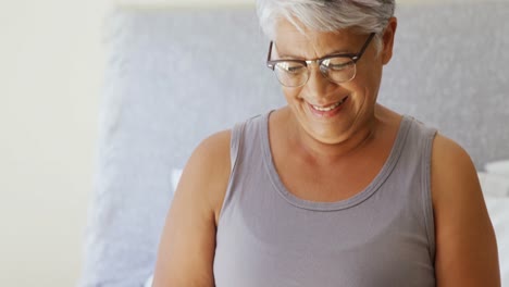 Happy-senior-woman-reading-book-while-sitting-on-bed-in-the-bed-room-4k