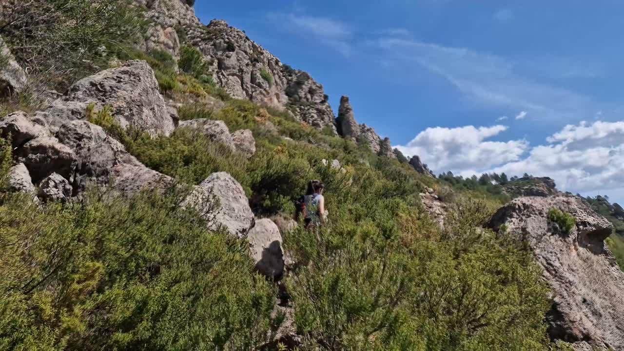 una mujer caminando por una colina rocosa en las montañas españolas.