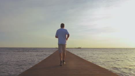 Man-jogging-on-the-pier-at-sunset