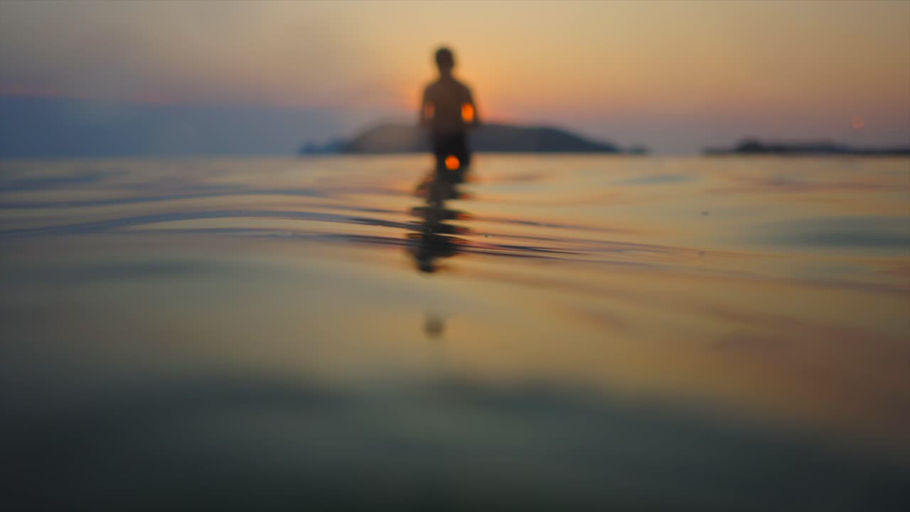 Silhouette of a Person Standing in Water at Sunset or Sunrise