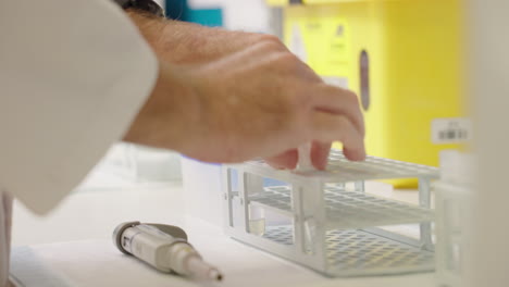 close up of medical research scientist placing blood tubes into test tube rack on laboratory bench, 4k