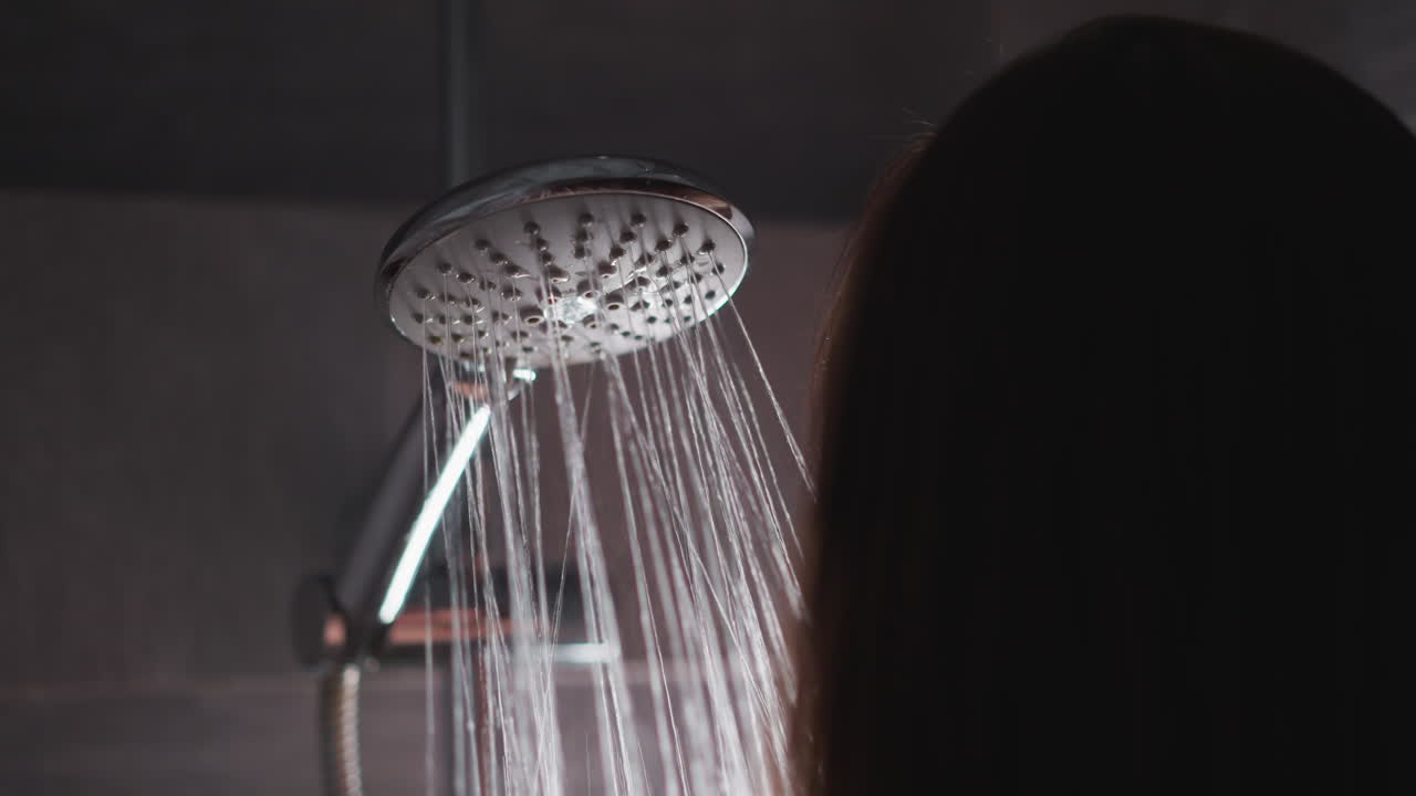 mujer tomando una ducha caliente para limpiar el cuerpo y la cabeza. dama haciendo rutina de limpieza nocturna en la ducha. mujer morena disfruta de una fuerte presión de agua