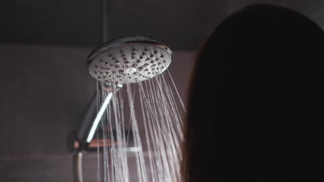 woman taking hot shower to clean body and head. lady doing evening cleansing routine in shower. female brunette enjoys strong pressure of water