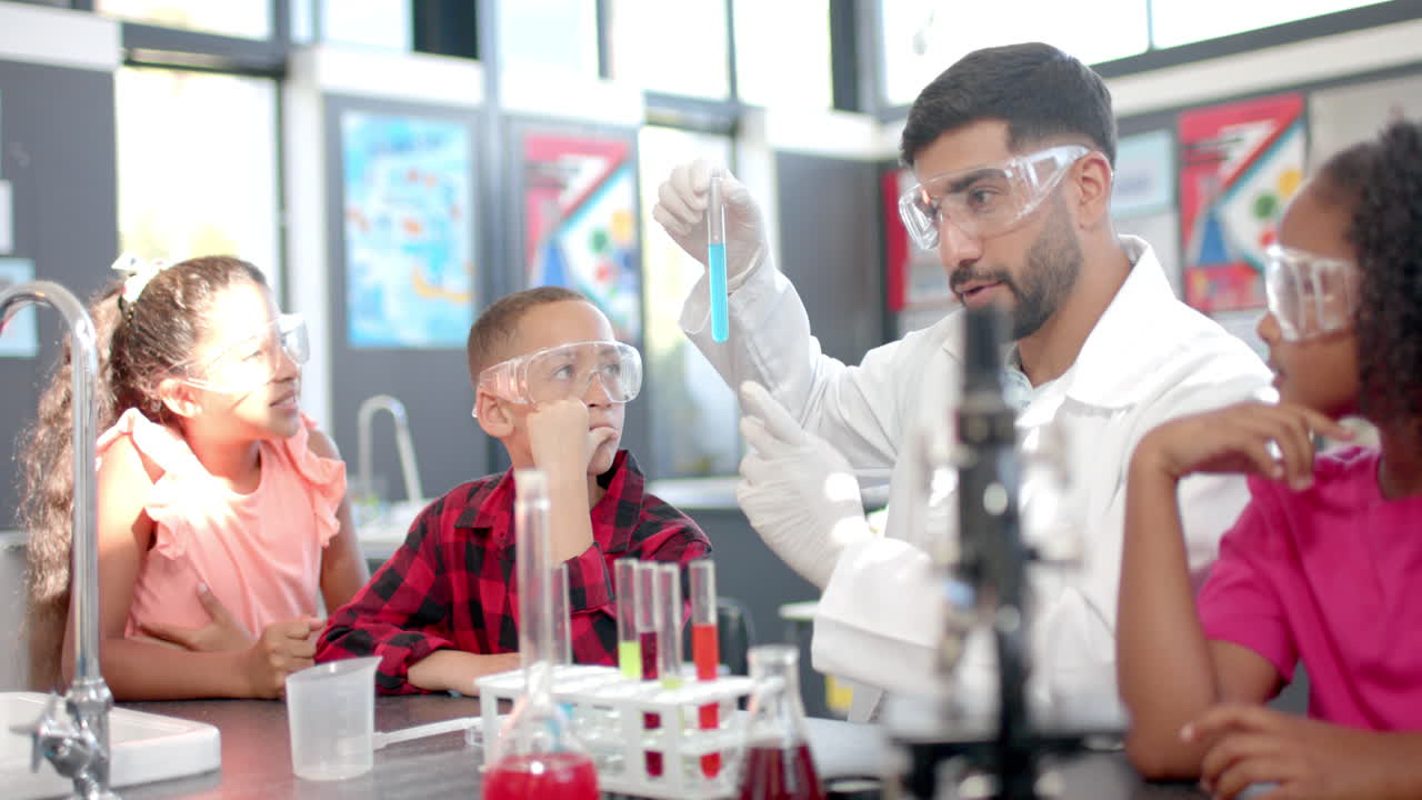 In a school classroom, a biracial teacher demonstrates a chemistry experiment