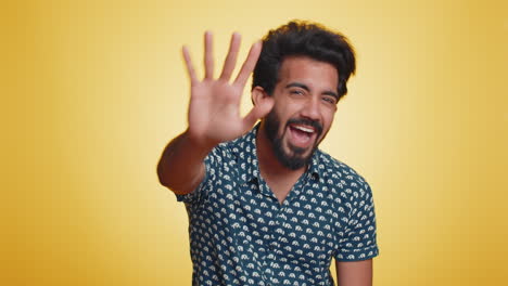 indian man holding hand above eyes forehead, peering into distance searching someone, waving hello