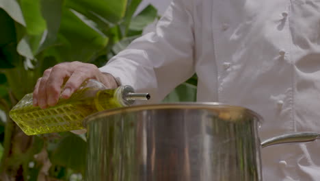 chef vertiendo aceite de oliva virgen extra en una sartén de metal