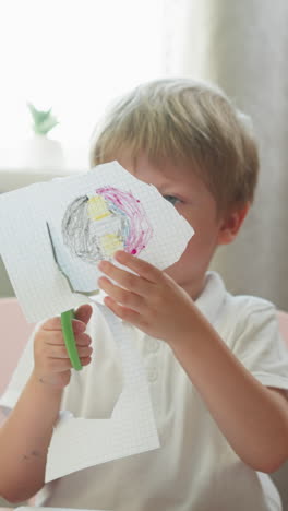 diligent little boy cuts out circle with drawing of copybook page at table in classroom. toddler kid does creative craft work at kindergarten lesson