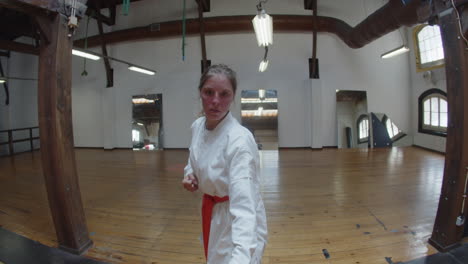 handheld shot of focused girl showing karate movements in gym