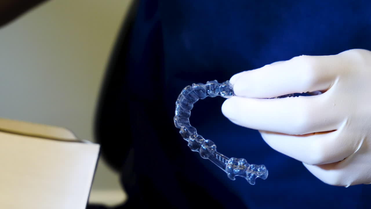 한 손으로 invisalign 리테이너를 들고 치과 의사의 중간 샷