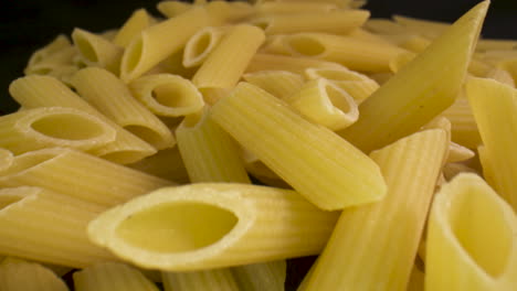 diapositiva macro a través de un montón de pasta penne sin cocer