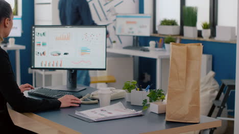 Cheerful-businesswoman-putting-food-takeaway-order-package-on-desk-table-during-lunchtime-break