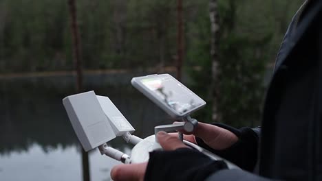 cierre de las manos del operador de drones controlando su drone con un controlador remoto dji para fotografía aérea o inspección, con espacio de copia