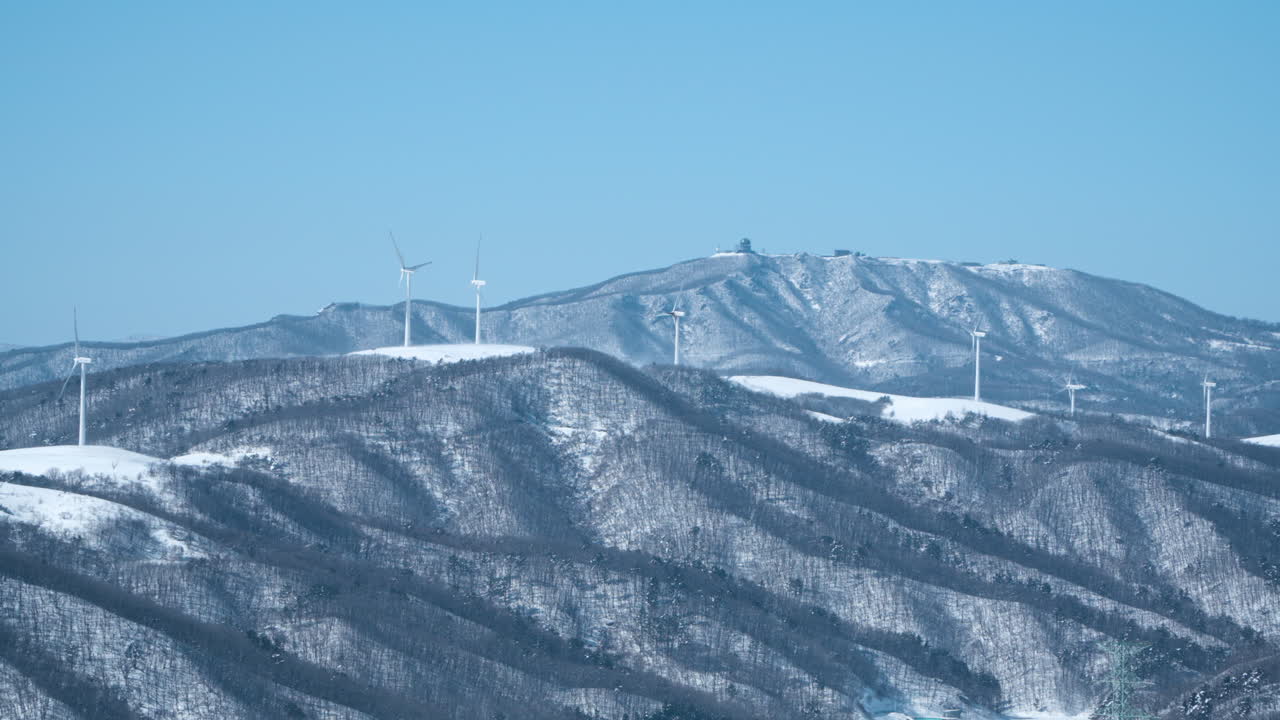남한의 다이그발리 스카이 랜치 (daeguallyeong sky ranch) 에서 회전하는 눈 인 산맥 꼭대기에 있는 풍력 터빈 농장