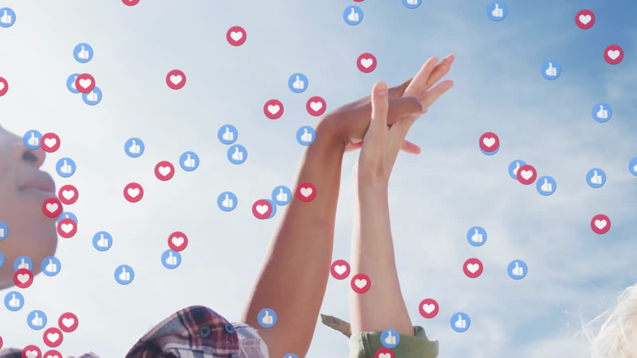 Two women raising hands outdoors, driving marketing campaign with floating thumbs-up hearts
