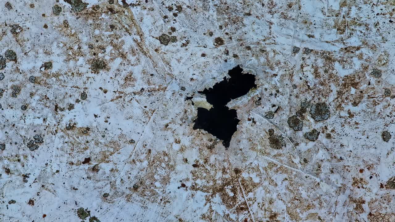 Superficie de tejado descuidada con un gran agujero, lo que indica deterioro y una necesidad crítica de reparación.