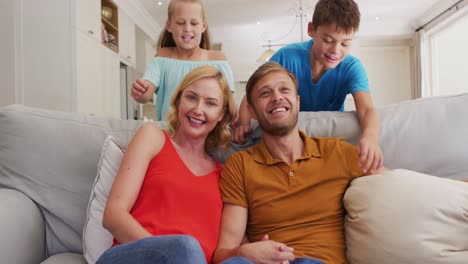 Portrait-of-happy-caucasian-parents,-son-and-daughter-sitting-at-home-on-sofa