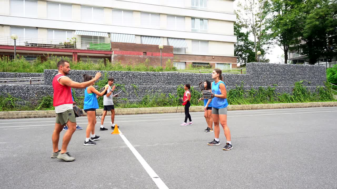 A group of adults doing baseball practice in a parking lot