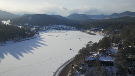 Winter-Etown-Evergreen-Lake-house-traffic-fishing-tents-Denver-golf-course-Colorado-aerial-drone-Ice-skating-skate-hockey-rink-pond-hockey-sunset-golden-hour-winter-snow-forward-pan-up-reveal-motion