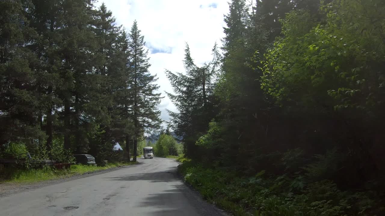 Looking out the back of the car while driving by trees and Spruce Creek at Resurrection Bay on Lowell Point