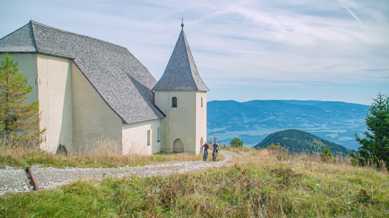 Picturesque mountain landscape with cyclists by a church