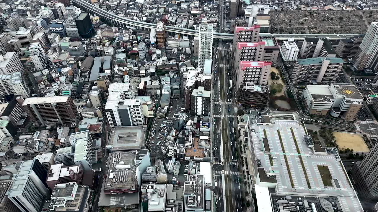 View of Osaka's dense urban landscape showcasing buildings, roads, and parking lots, as seen from Abeno Harukas. slow tilt up shot