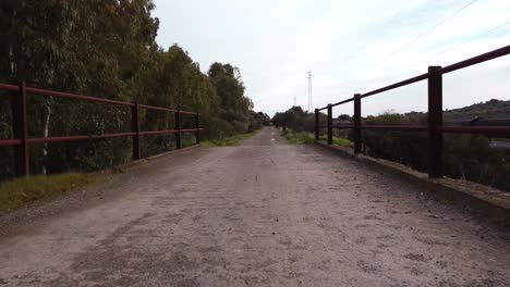 Low-aerial-drone-shot-of-rural-trail-in-Sardinia,-flying-over-small-bridge