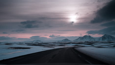 POV-driving-video-through-Northern-Iceland's-snowy-landscape-at-sunset,-capturing-serene-winter-beauty-and-soft-lighting