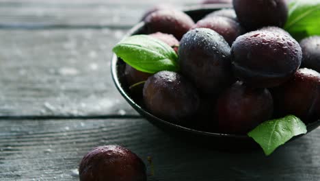 wet purple plums in bowl