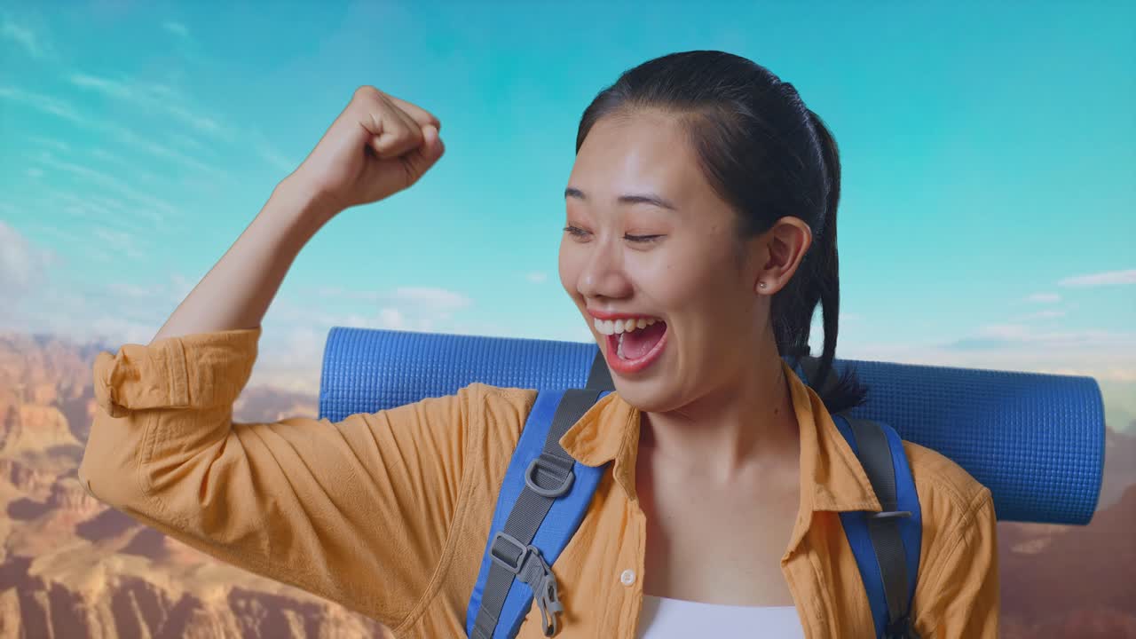 Close Up Of Asian Female Hiker With Mountaineering Backpack Smiling And Flexing Her Bicep While Traveling At The Top Of Mountain