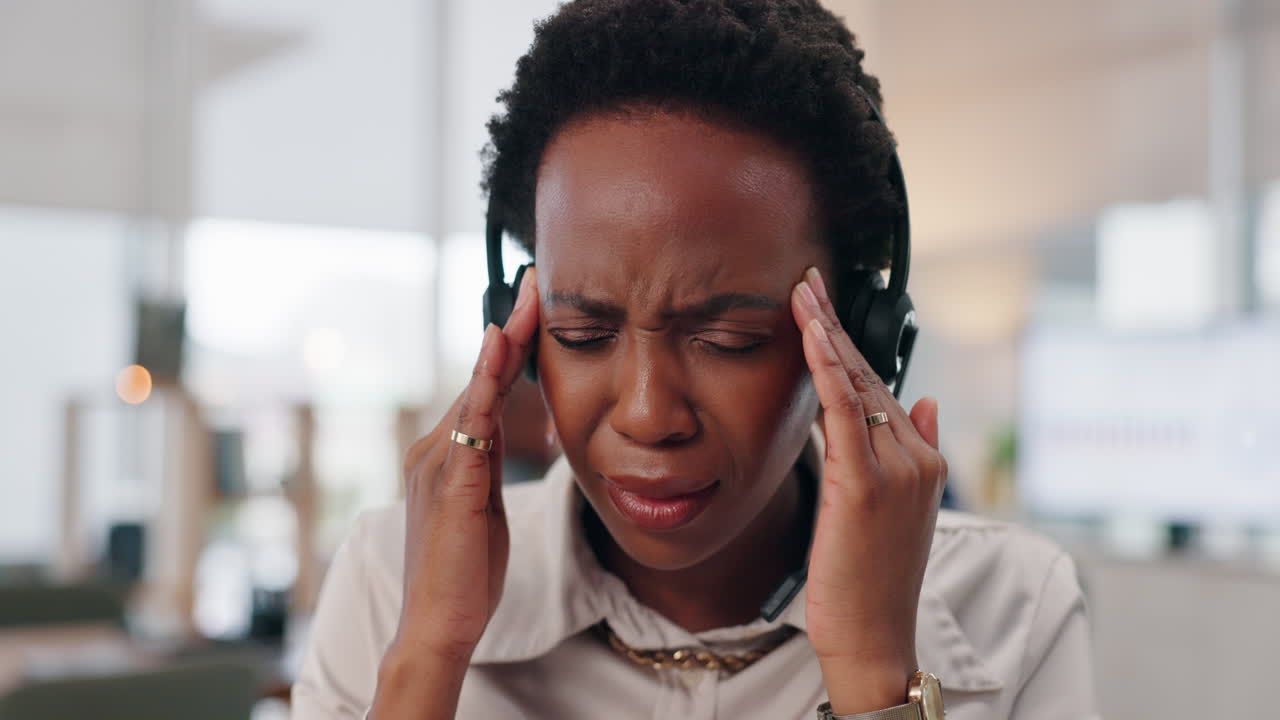 Woman with headache wearing headset in office