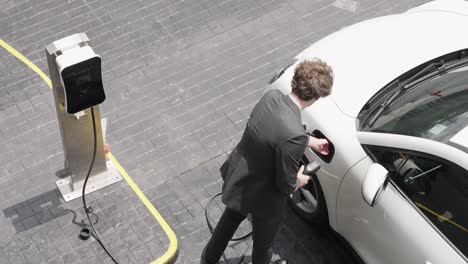 Progressive-businessman-plugs-charger-plug-from-charging-station-to-his-EV.