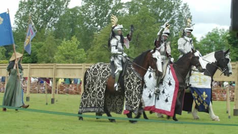 armoured knights riding their horses wave at the crowds as they enter the arena during a medieval tournament joust at leeds castle, kent, england