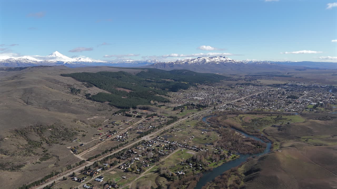 Junin de los Andes town, framed by the majestic andes mountains and a meandering Chimehuin River river in patagonia, argentina, drone panning shot
