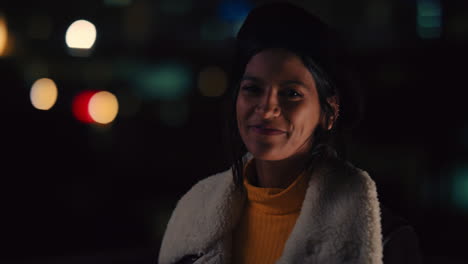 portrait beautiful mixed race woman on rooftop at night smiling happy enjoying urban nightlife with bokeh city lights in background