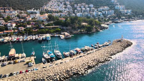 Close-up-drone-flight-over-the-water-surface-of-the-yacht-boat-mooring-against-the-backdrop-of-a-resort-town-located-between-green-hills