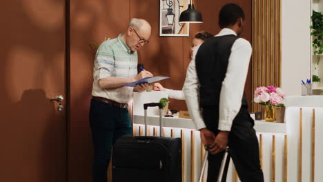 Senior-guy-at-front-desk-doing-check-in