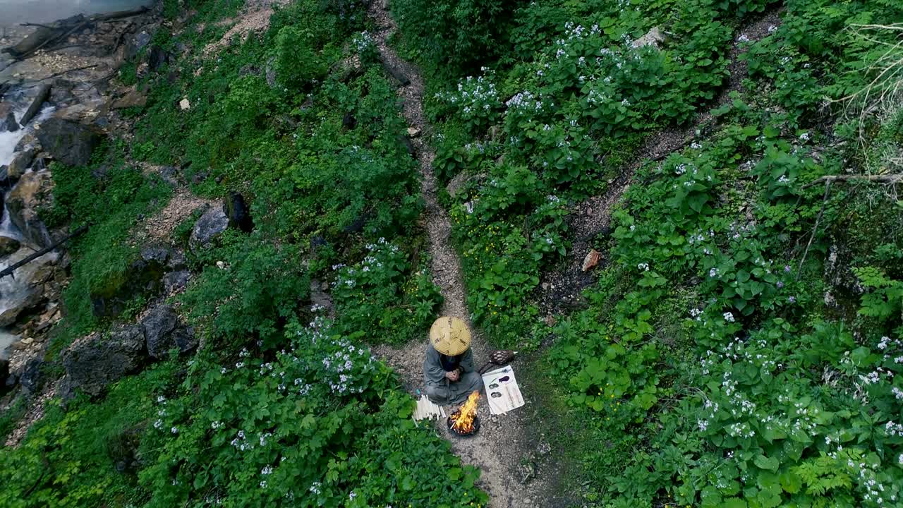 hombre con barba hace una ceremonia de fuego frente a una gran cascada
