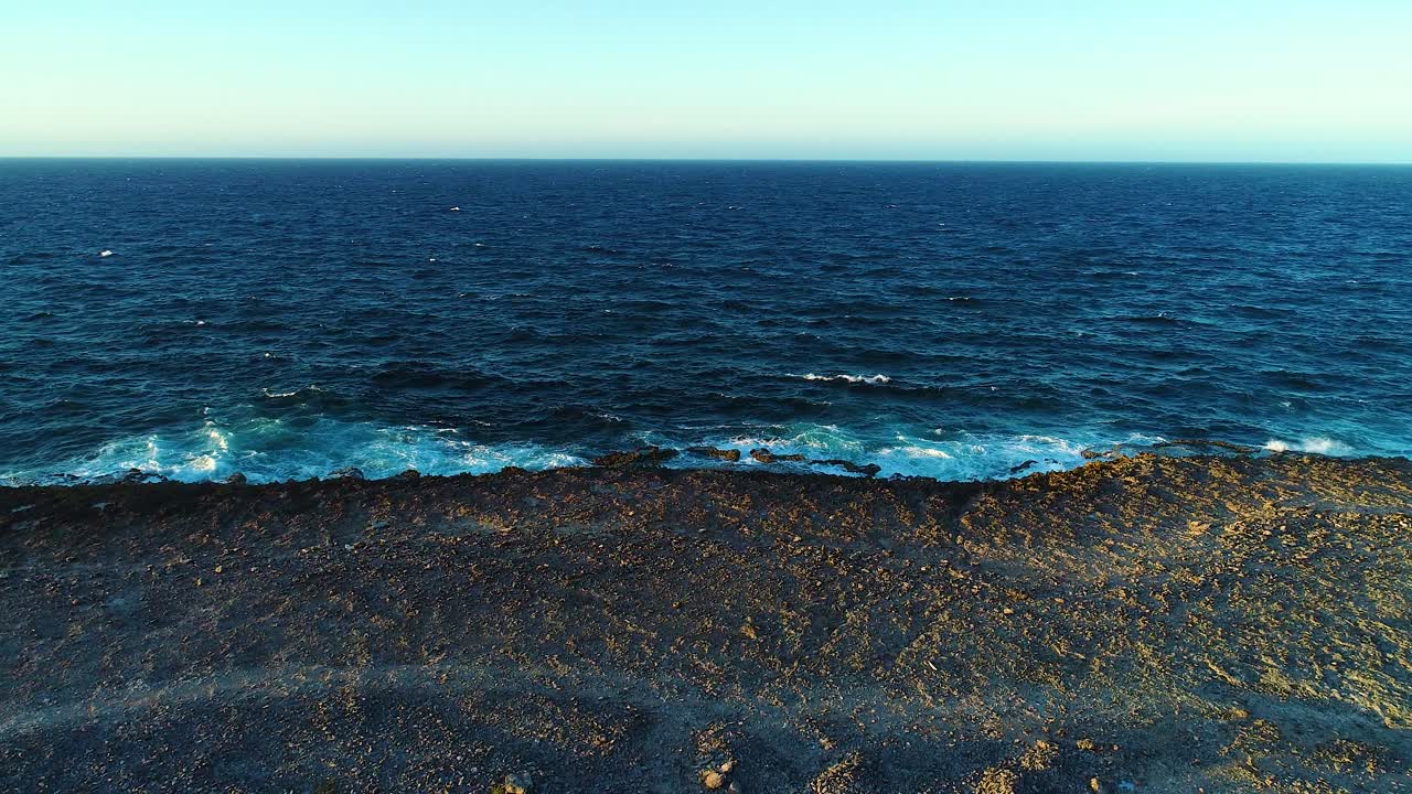 el avión no tripulado se eleva y se inclina hacia abajo a través del paisaje de la playa volcánica mirando hacia el horizonte en la hora dorada
