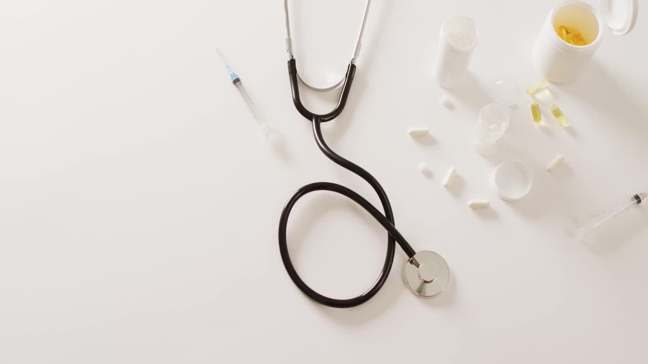 Video di stetoscopio, siringa, pillole e capsule su sfondo bianco con spazio per il testo